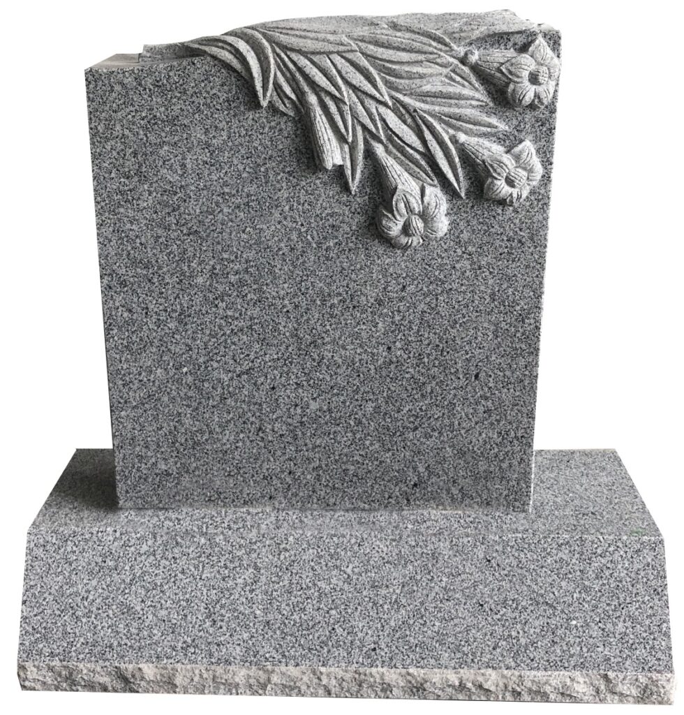 Classic Serp 9 (small) Gray tombstone with a sculpted floral design, set against a green landscape, symbolizing remembrance and honoring the deceased.