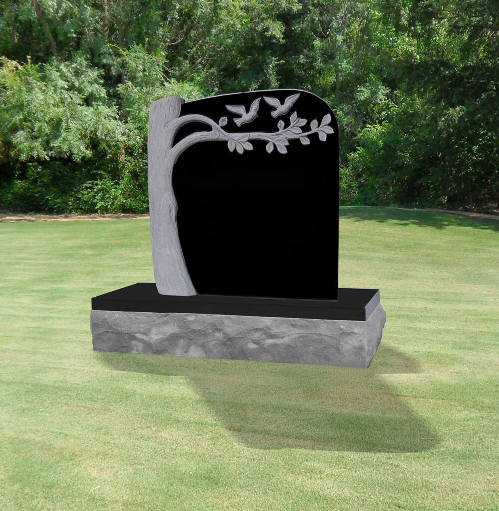 Memorial headstone featuring a carved tree and birds, set on a textured gray base, surrounded by a green grassy area, symbolizing peace and remembrance.